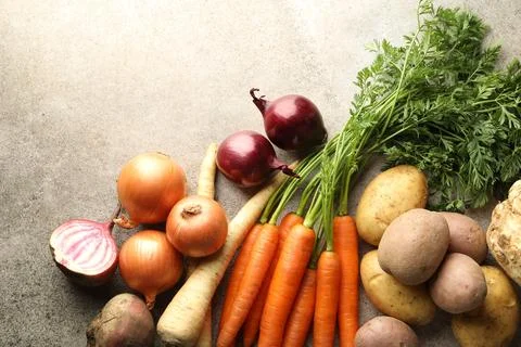 Different root vegetables on grey table, flat lay. Space for text Stock Photos