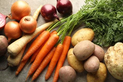 Different root vegetables on grey table, flat lay Stock Photos
