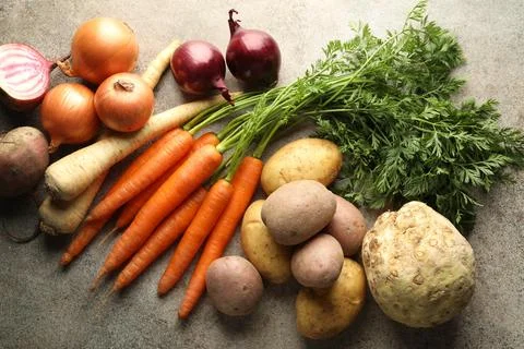 Different root vegetables on grey table, flat lay Stock Photos