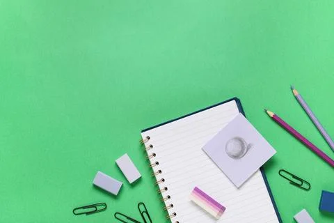 Different rubber erasers with notebook and stationery on green background Stock Photos