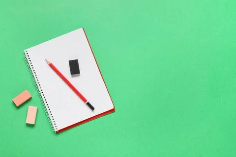 Different rubber erasers with notebook and pencil on green background 库存照片