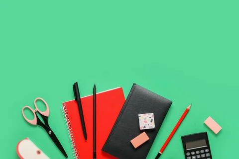 Different rubber erasers with notebooks and stationery on green background 库存照片