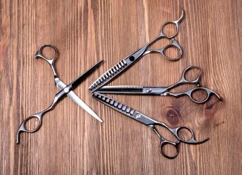 Different scissors on brown wooden table Stock Photos