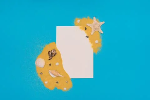 Different sea shells and starfish on bright yellow sand with white paper card Stock Photos
