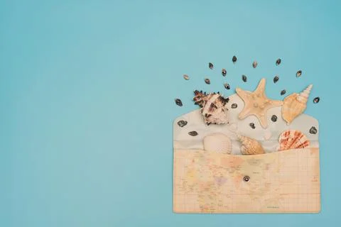 Different sea shells and starfish lay in opened envelope with map print on it on Stock Photos