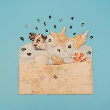 Different sea shells and starfish lay in opened envelope with map print on it on Stock Photos