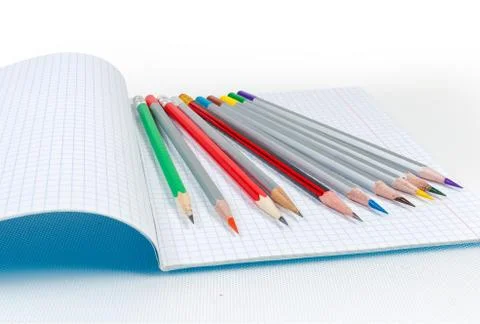 Different sharp pencils laid out on the open exercise book Stock Photos