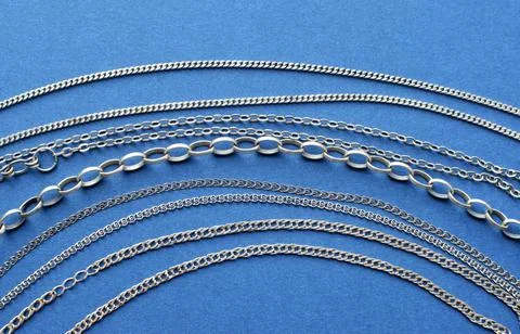 Different silver chains lie on a blue background. Jewelry for women and men Foto stock