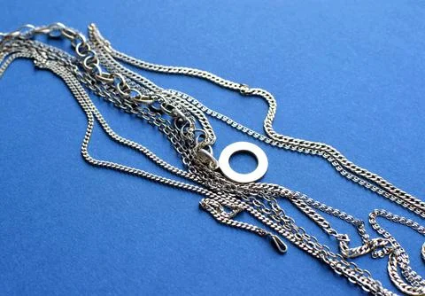 Different silver chains lie on a blue background. Jewelry for women and men Stock Photos