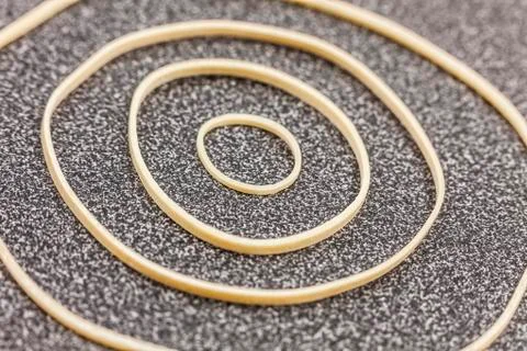 Different size rubber bands form a circular design on office desktop Stock Photos