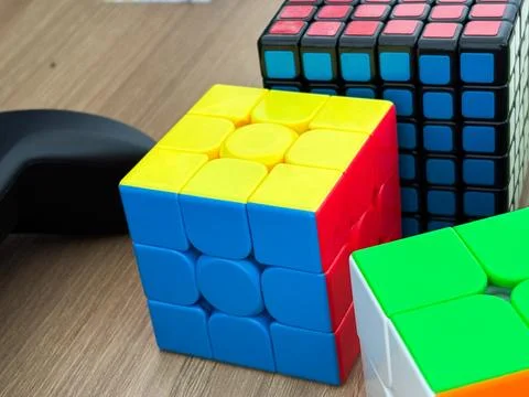 Different Size Rubik's Cubes - 2x2, 3x3, and 5x5 Speed Cubes Wooden Background Stock Photos