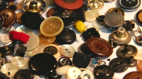 Different  sized colored  buttons  scattered on white tablecloth - slow motion Stock Footage 44299967