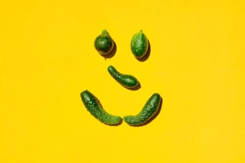 Different sizes and forms cucumbers on a yellow background forms a smiling fa 写真素材