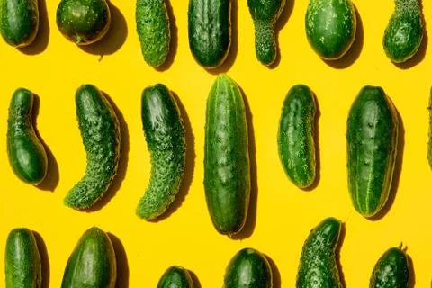 Different sizes forms cucumbers pattern on a light yellow background. Copy sp Stock Photos