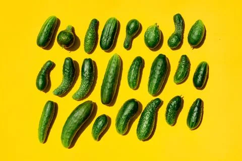 Different sizes forms cucumbers pattern on a light yellow background. Copy sp Stock Photos