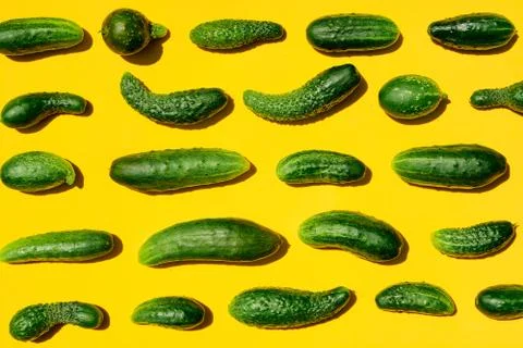 Different sizes forms cucumbers pattern on a light yellow background. Copy sp Stock Photos