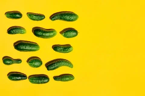 Different sizes forms cucumbers pattern on a light yellow background. Copy sp Stock Photos