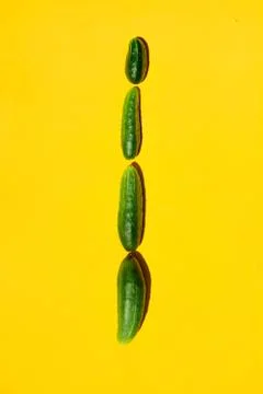 Different sizes forms cucumbers on a yellow background form a row. Stock-Fotos