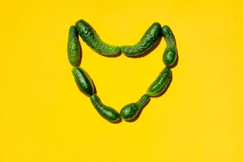 Different sizes forms cucumbers on a yellow background form a heart simbol. 写真素材