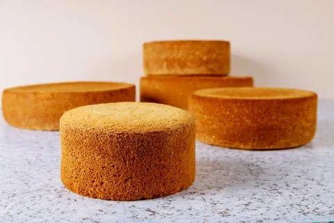 Different sizes sponge cakes on table. Stock Photos