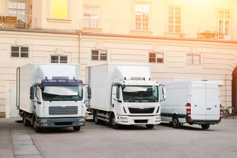 Different small and medium courier service trucks and van at building courtyard Stock Photos