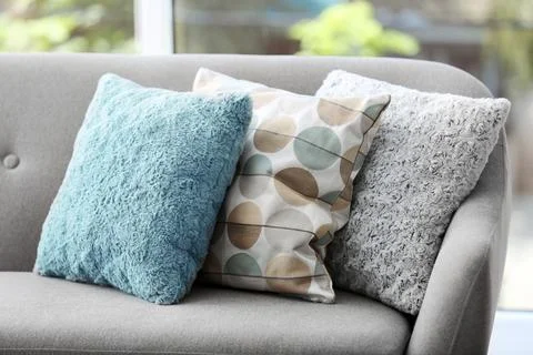 Different soft pillows on sofa in room. Interior element Stock Photos