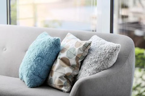 Different soft pillows on sofa in room. Interior element Stock Photos
