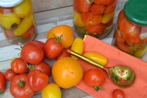 Different sort of tomatoes on wooden table with marinated tomatoes Stock Photos