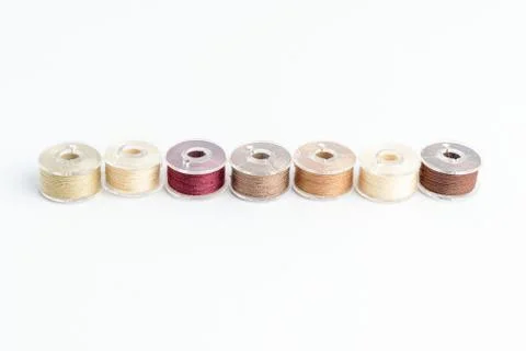 Different spools of mixed beige and brown cotton thread prepared for sewing Foto stock