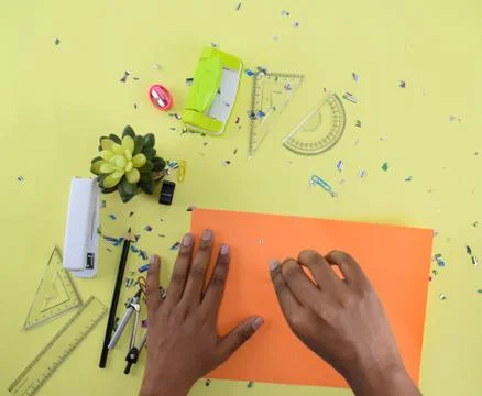 Different study materials scattered on a yellow paper background while a pers Stock Photos