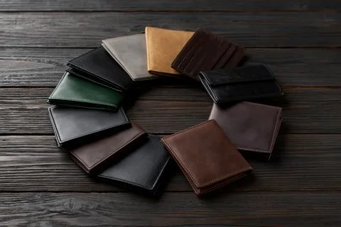 Different styles of wallets arranged in a circle on a wooden table in a wel.. 스톡 사진