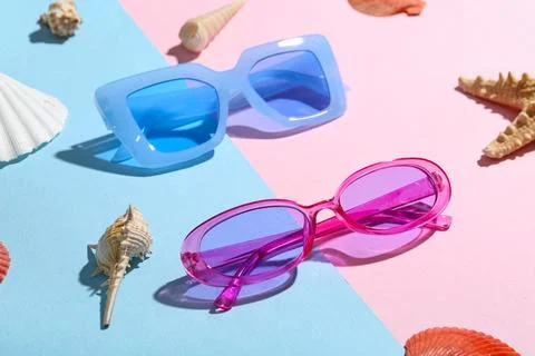 Different stylish sunglasses and seashells on colorful background, closeup Stock Photos