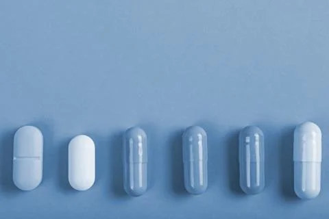 Different tablets capsules on tinted background Stock Photos