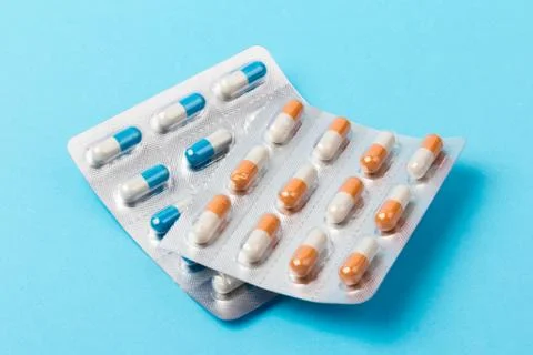 Different tablets, pills in foil blister packs, medical drugs on blue backgro Foto stock