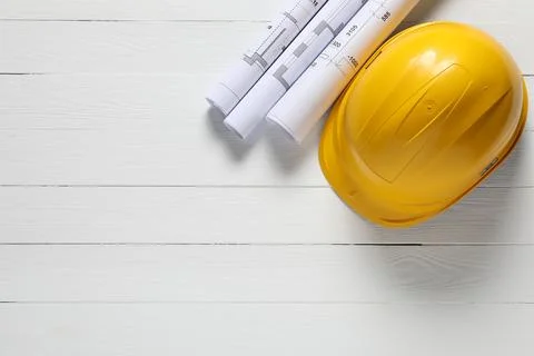 Different technical drawings and hard hat on white wooden table, flat lay. .. Stock Photos