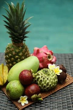 Different tropical fruit on wicker table near swimming pool Stock Photos