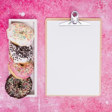 Different type donuts white rectangular box near clipboard with white paper Stockfoto's
