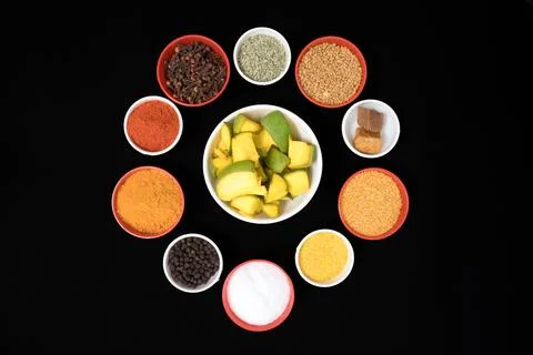 Different type of spices filled in bowls in circular shape with green mango Foto stock
