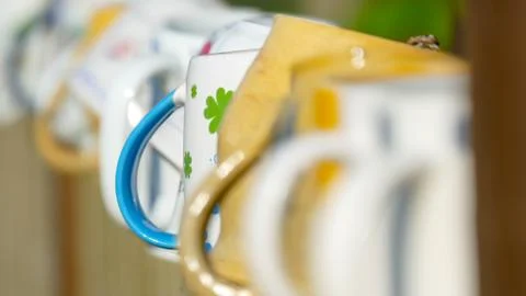 Different types and shapes of cups and mugs hanged upside down on the fence Stock Photos