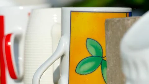 Different types and shapes of cups and mugs hanged upside down on the fence Stock Photos