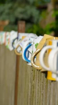 Different types and shapes of cups and mugs hanged upside down on the fence Stock Photos