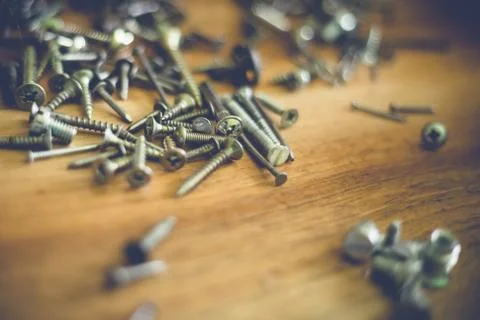 Different types and sizes of nails and screws on a wooden table Foto stock