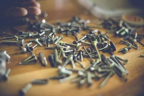 Different types and sizes of nails and screws on a wooden table Foto stock