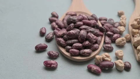 Different types of beans in wooden spoons on gray stone table. Stock Footage 130241669