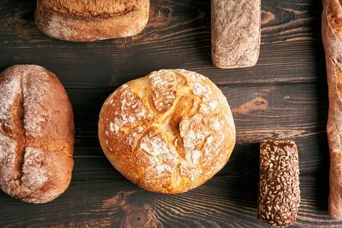 Different types of bread loaves on dark wooden background Stock-Fotos