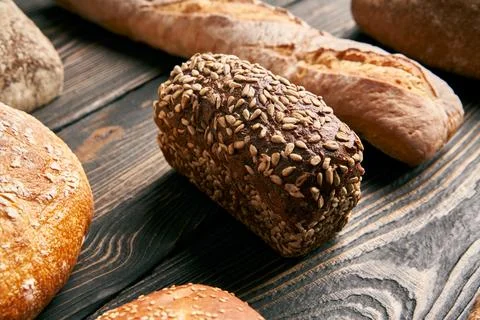 Different types of bread loaves on dark wooden background Stock-Fotos