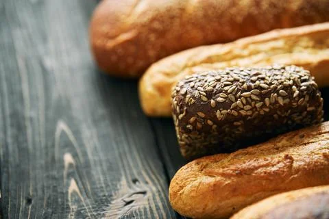 Different types of bread loaves on dark wooden background with copy space Stock Photos