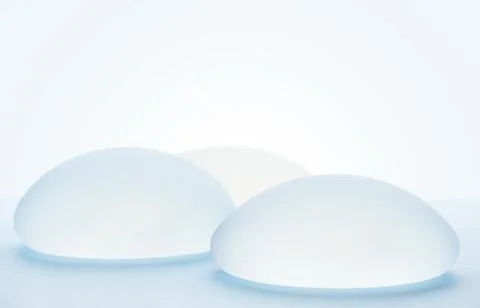 Different types of breast implants on blue background. Copy space Stock Photos