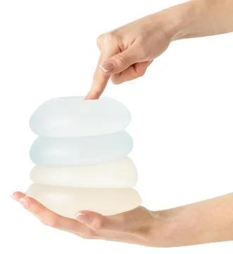 Different types of breast implants in hand on white background, clipping path. Stock Photos