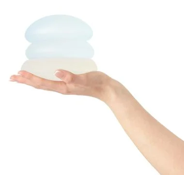 Different types of breast implants in hand on white background, clipping path. Stock Photos